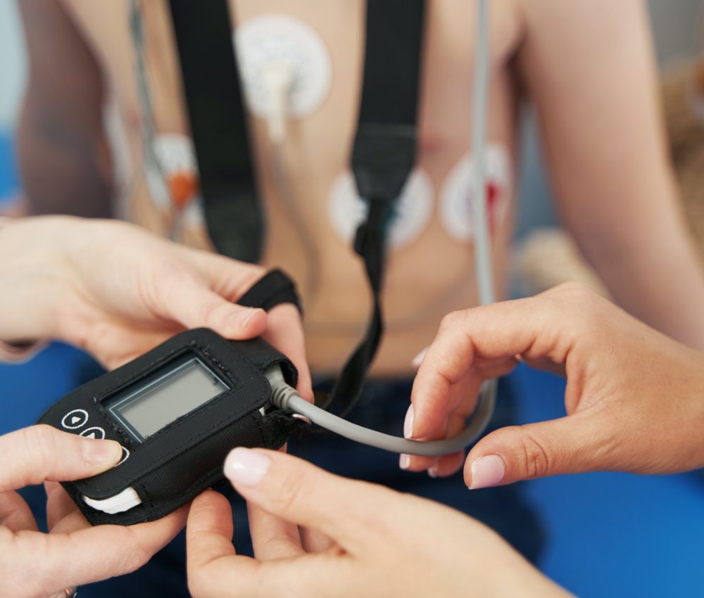 Doctor showing ECG holter monitor to patient in pediatric clinic