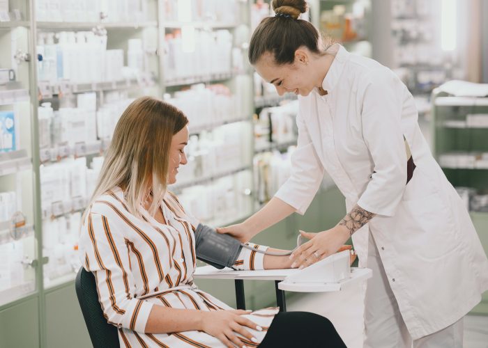 Trainee taking blood pressure of his customer in the pharmacy