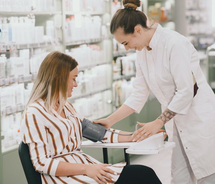 Trainee taking blood pressure of his customer in the pharmacy